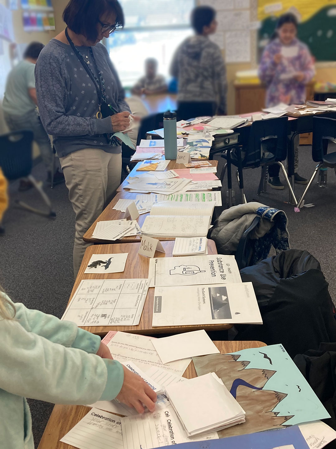 A teacher provides feedback to students during an Exhibition of Learning.